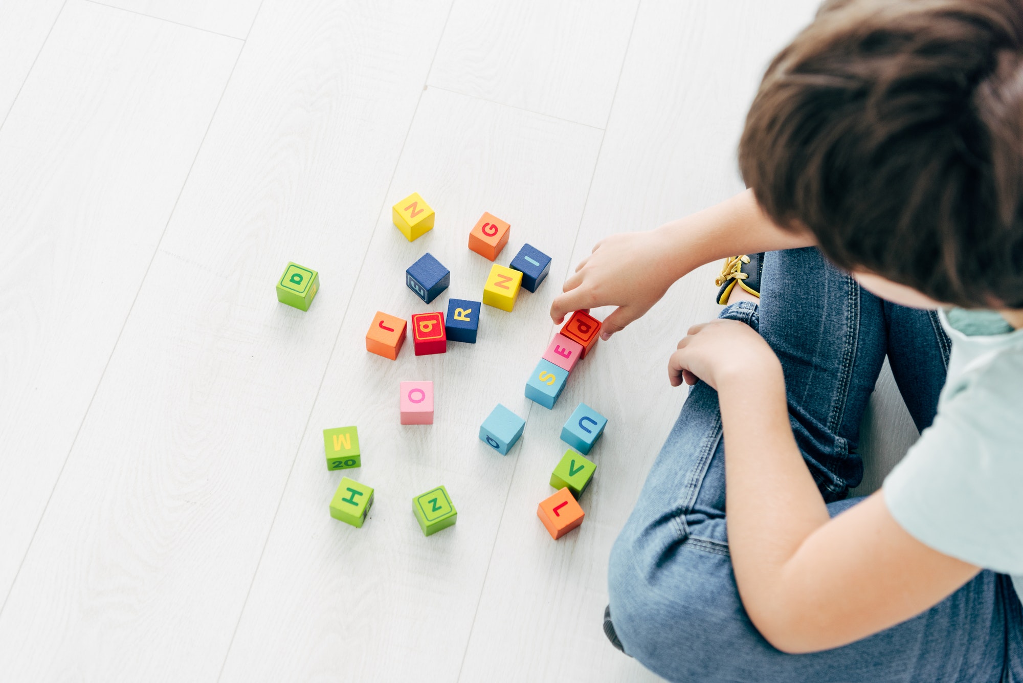 cropped view of kid with dyslexia playing with colorful building blocks