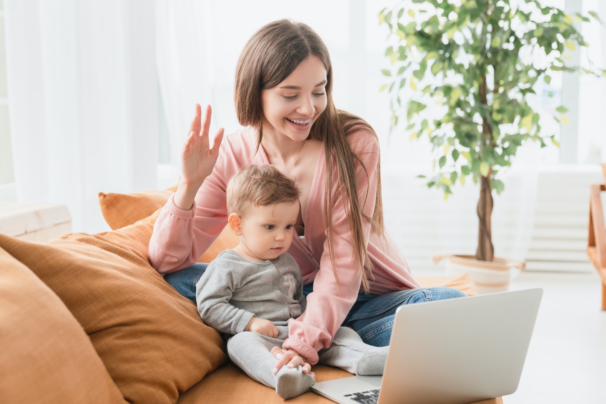 Happy young mother with toddler infant newborn baby having video call online conference