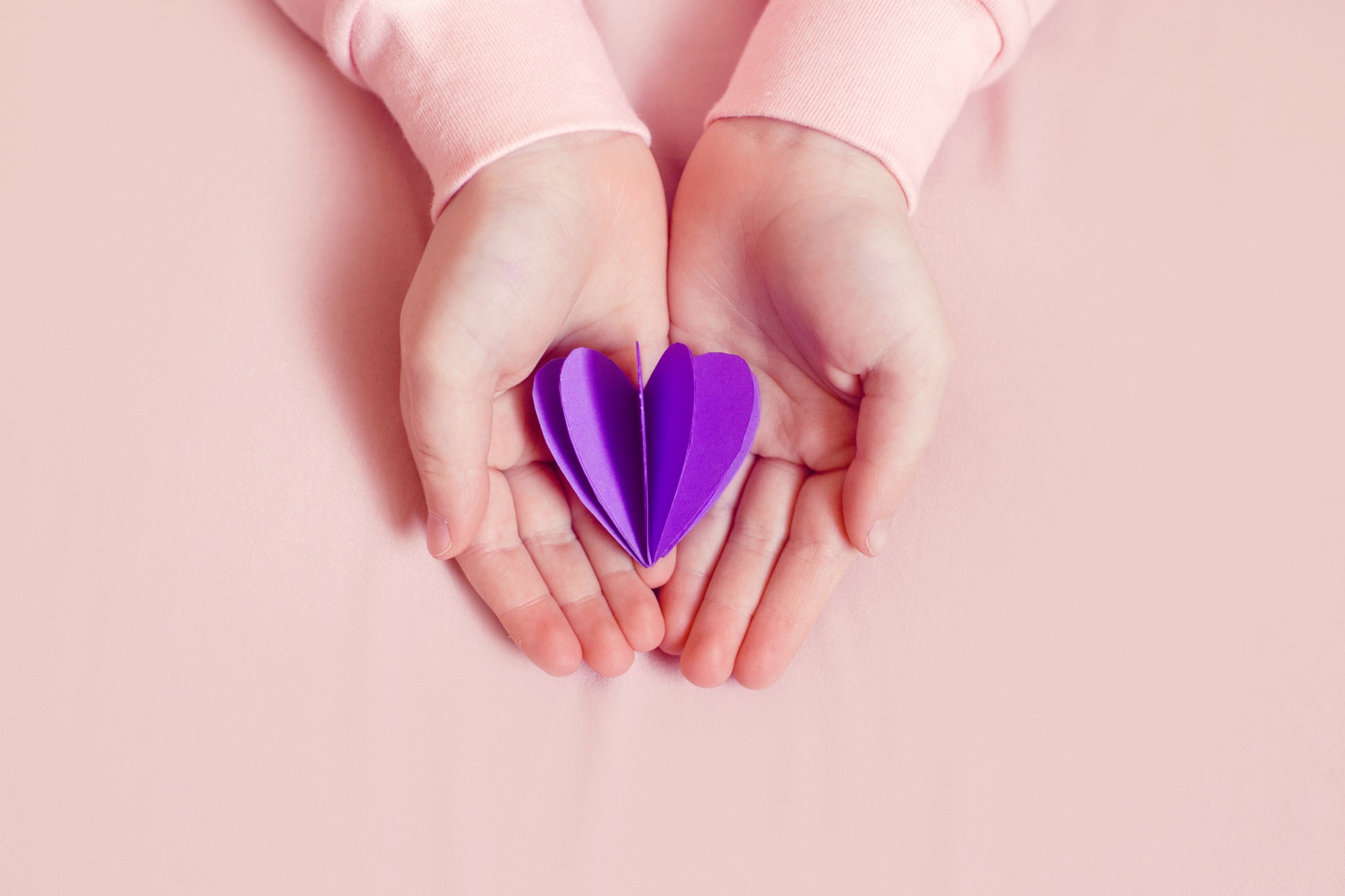 Kids child hands holding purple violet paper heart. Epilepsy awareness day. Care, health, support.